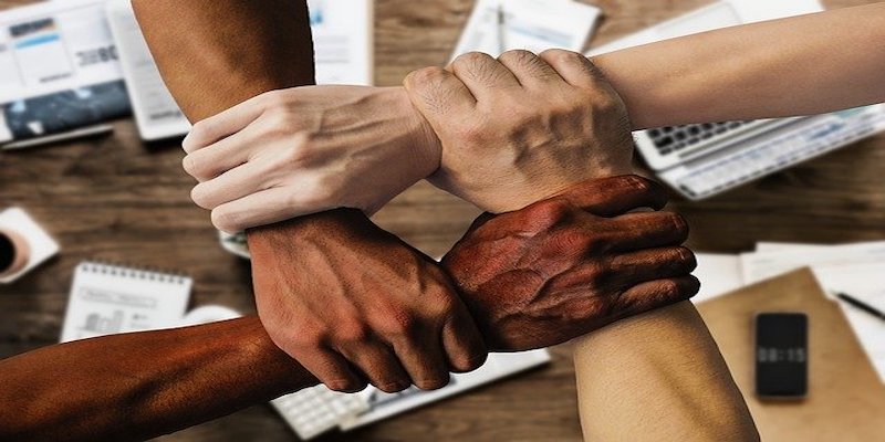 group of people holding arms to signify teamwork