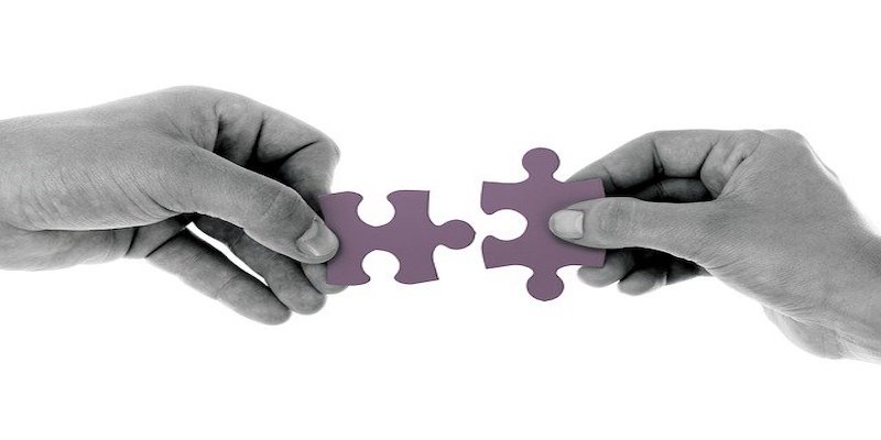 two people holding jigsaw pieces that fit together