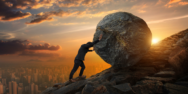 man pushing boulder uphill